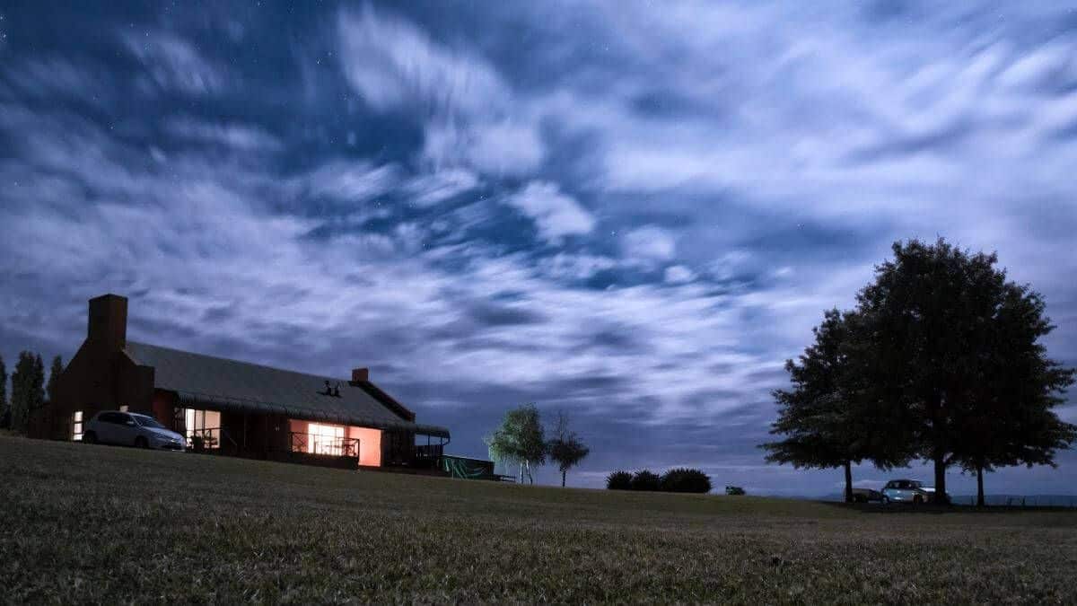 Illuminated house and garden under cloudy sky