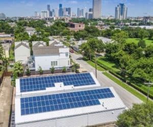 Commercial building with solar panels on roof in a residential neighborhood and downtown Houston in the back
