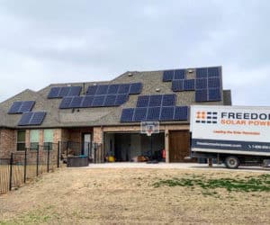 House with solar panels on the roof and a Freedom Solar truck parked out front