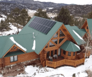 Top view of cabin in Colorado with installed solar panels on roof and snow around