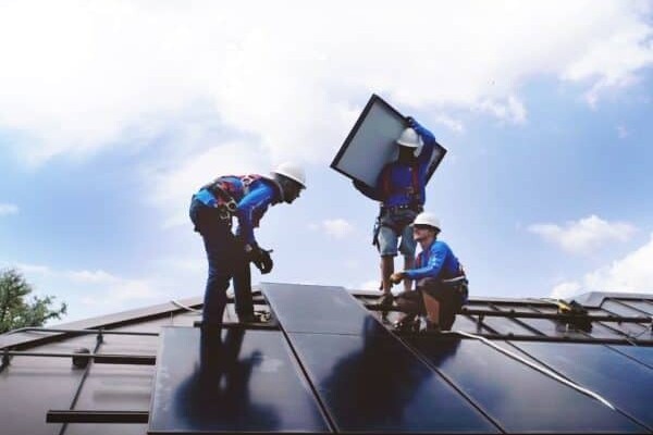 Three solar panel installers on a roof
