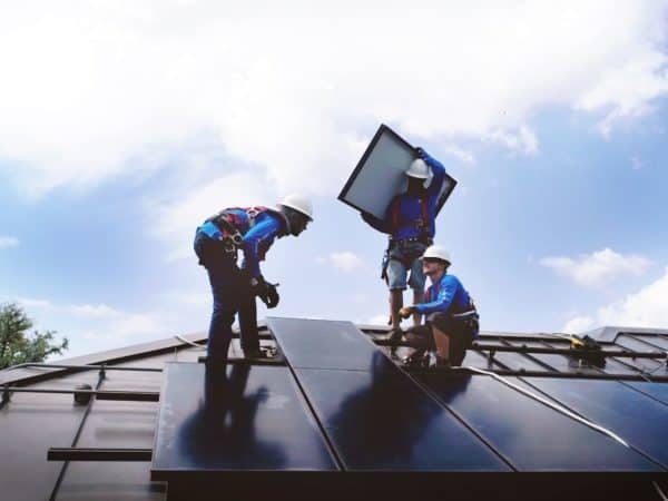 Three solar panel installers on a roof