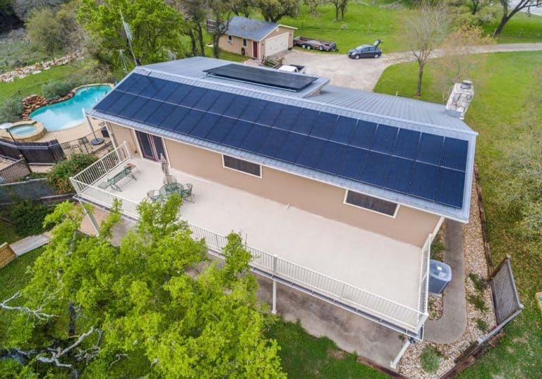 Side view of house in Live Oak, Buda, Texas with solar panels on the roof and view of the pool in the backyard