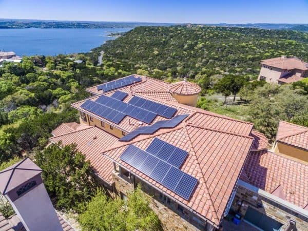 View of the roof of a house with solar panels on the roof, green areas around it and the Colorado River next to it in Cielo Azul, Austin, Texas
