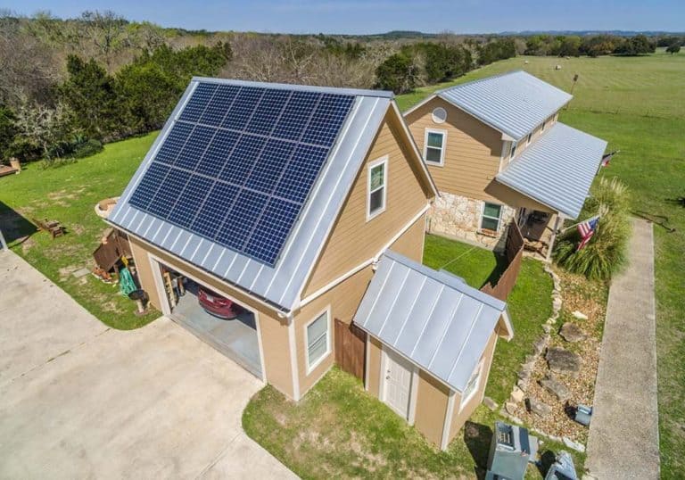 Side view of house with solar panels on the roof and green areas around it in Boerne, Texas