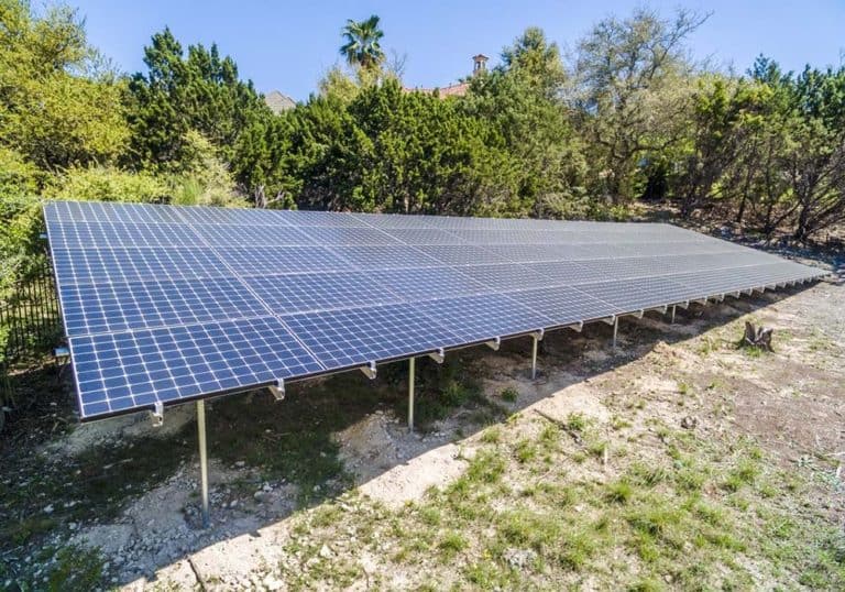 Close-up view of solar panels installed on ground in a residential neighborhood in Chalk Knoll, Austin, Texas and trees around