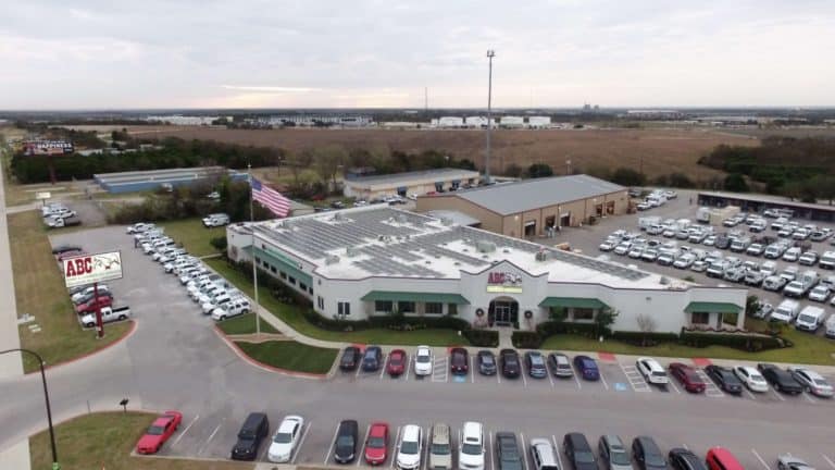 Aerial shot of ABC Home and Commercial building in Austin, Texas with solar panels installed on the roof and parking lot around it