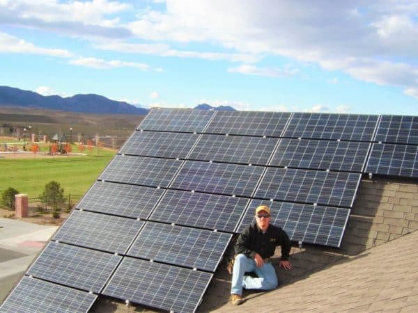 Freedom Solar technician sitting on roof next to solar panels