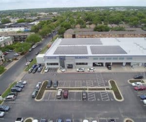 Front view of Austin Subaru dealership in Austin, Texas with array of solar panels on roof and parking lot