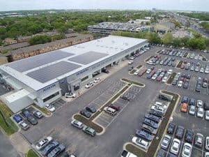 Drone view of dealership Austin Subaru with array of solar panels on roof and parking lot view