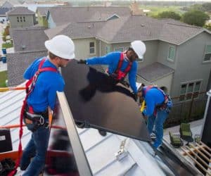 Three Freedom Solar technicians installing solar panels on a  house roof