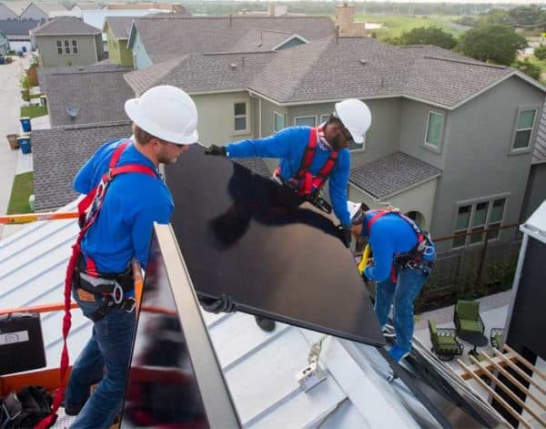 Three solar panel installers on a roof