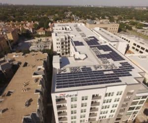 Drone view of residential building with array of solar panels on roof