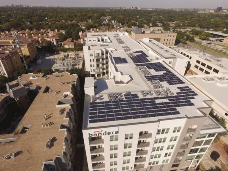 Drone view of residential building with array of solar panels on roof