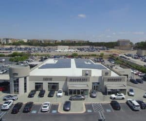 Front view of Alfa Romeo and Maserati dealership in San Antonio, Texas with solar panels on roof and parking lot view