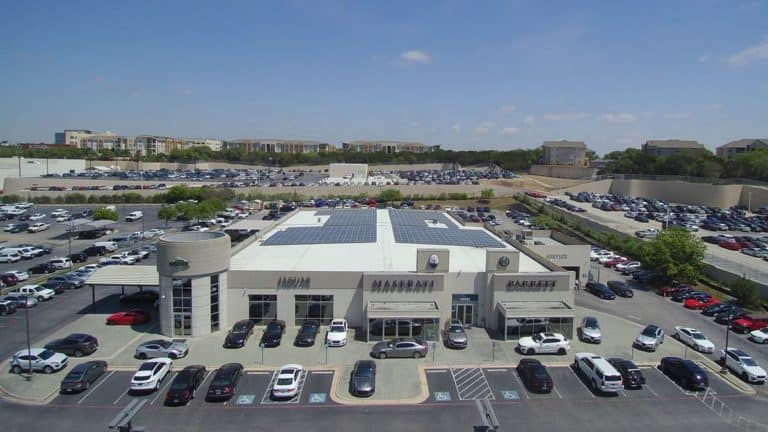 Front view of Alfa Romeo and Maserati dealership in San Antonio, Texas with solar panels on roof and parking lot view