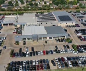 Drone view of Bob Tomes Ford dealership in McKinney, Texas array of solar panels installed on roof and cars parked