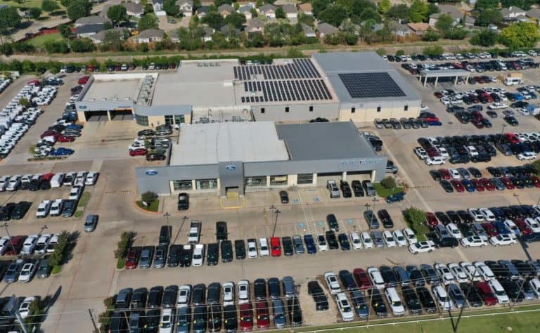 Drone view of Bob Tomes Ford dealership in McKinney, Texas array of solar panels installed on roof and cars parked