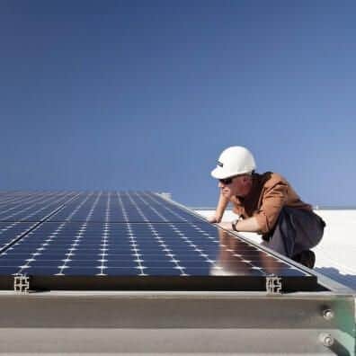 Installation technician inspecting solar panels on a roof