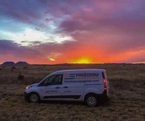Freedom Solar's van parked in open field at sunset