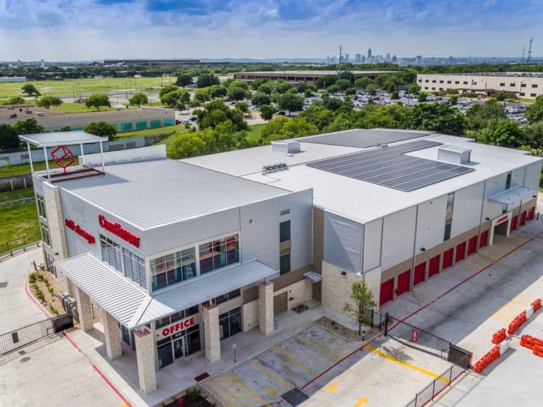 Side view of CubeSmart self storage in Texas with solar panels on the roof and building behind