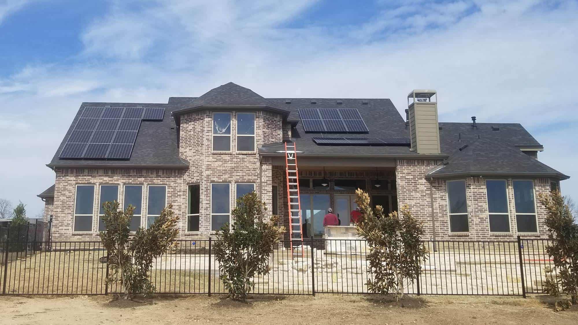 House front with men installing solar panels on the roof in Arlington, Texas