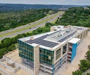 Back side of Davenport 360 building in Austin, Texas and man installing solar panels on the roof