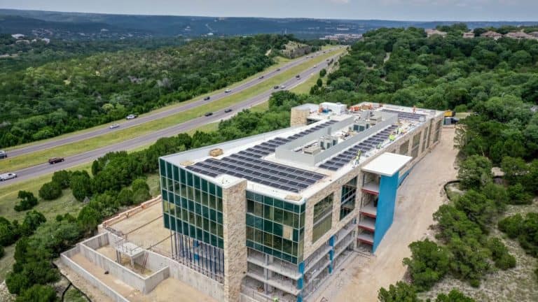 Back side of Davenport 360 building in Austin, Texas and man installing solar panels on the roof