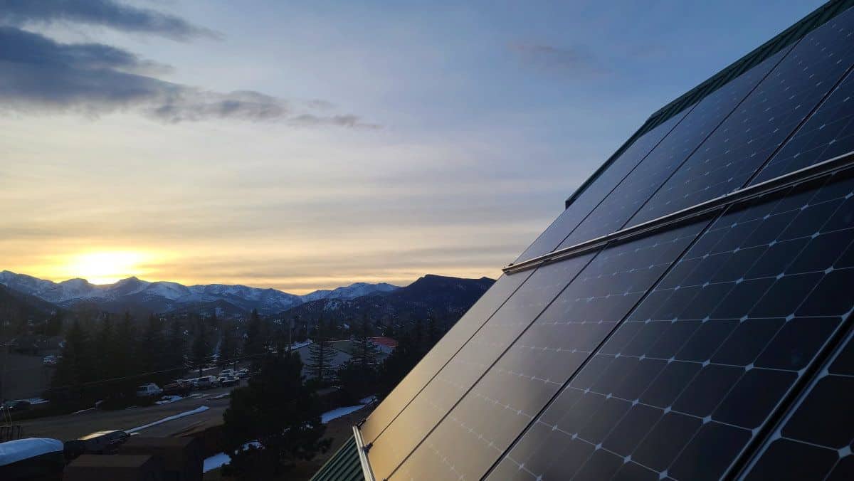 Close-up of solar panels installed on the roof and Denver mountains in the back