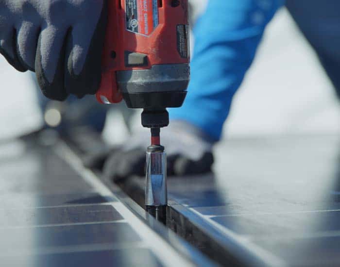 Freedom Solar technician installing solar panel with drill