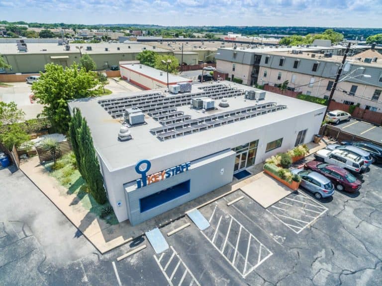 Front side aerial view of Key Staff building in San Antonio, Texas with solar panels on the roof and parked cars