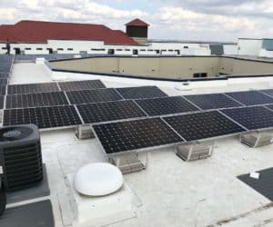 Building roof in Laurel Glen, San Antonio, Texas with solar panels installed and men behind