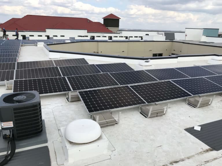 Building roof in Laurel Glen, San Antonio, Texas with solar panels installed and men behind