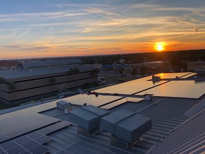 Drone roof view of The Northtown Professional Plaza in Laredo with array of solar panels installed and sunset in the back