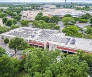 Drone view of South Austin Medical Clinic in Austin, Texas with solar panels on the roof and buildings around