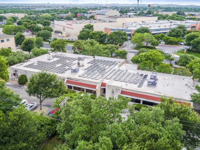 Drone view of South Austin Medical Clinic in Austin, Texas with solar panels on the roof and buildings around