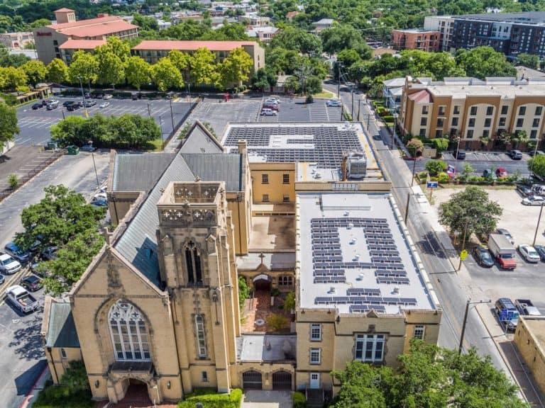 Drone view of the entrance of St. John's Lutheran Church with solar panels on the roof and residential area around