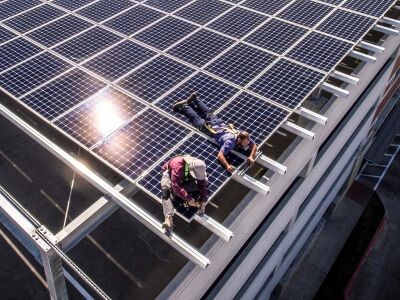Two technicians on a commercial building roof installing solar panels