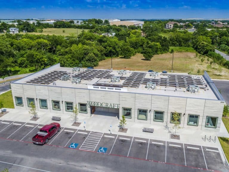 Woodcraft entrance in Austin, Texas with solar panels installed on the roof and green areas around