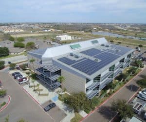 Apartment complex with array of solar panels installed on the roof and parking lot view