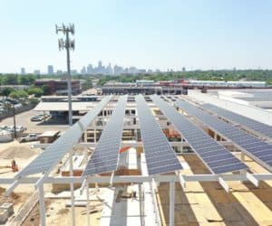 Installation of solar panels on roof of commercial building with downtown view behind