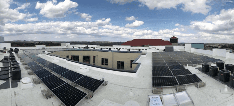 Apartment complex roof view with solar panels installed under bright blue sky