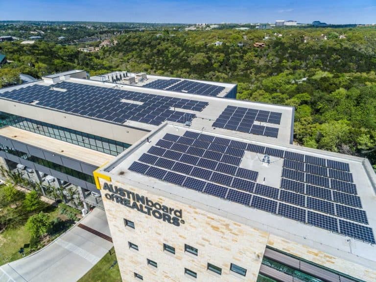 Roof view of Austin Board of Realtor's building with solar panels installed and trees behind
