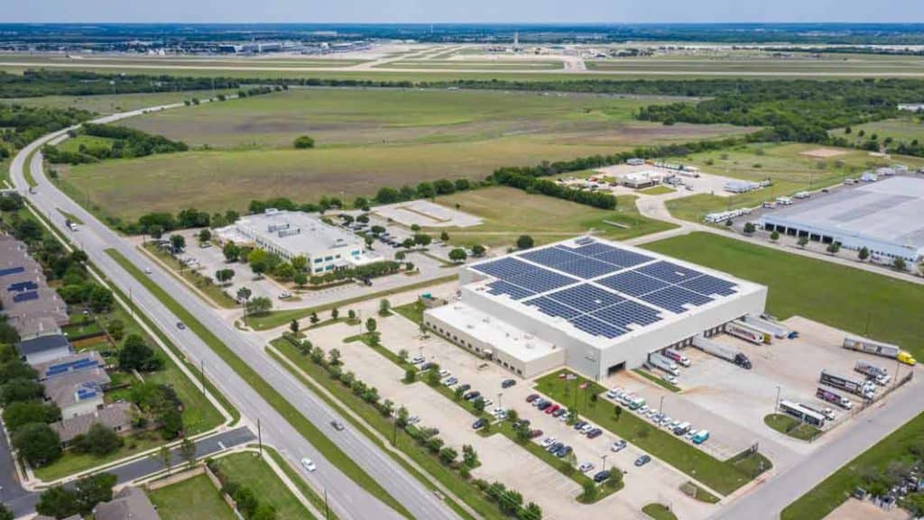 Drone view of Ben E. Keith Company building in Fort Worth, Texas with array of solar panels installed on the roof and green areas around