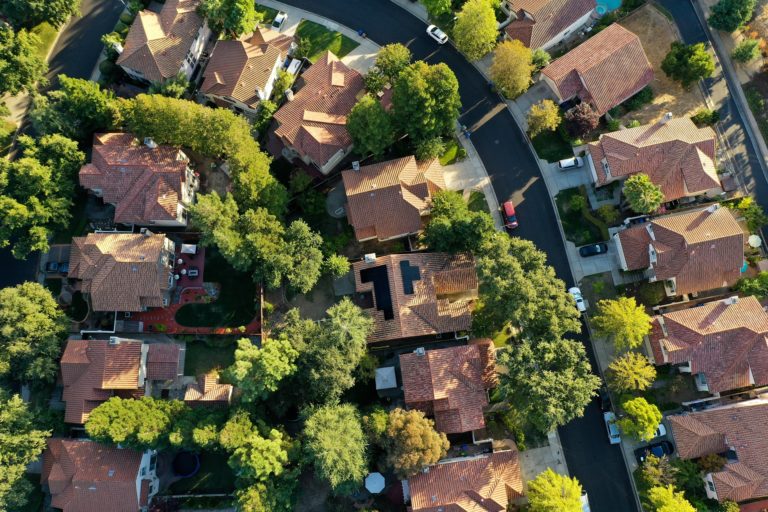 A birds-eye view photo taken by a drone above a neighborhood with solar panels atop certain houses.