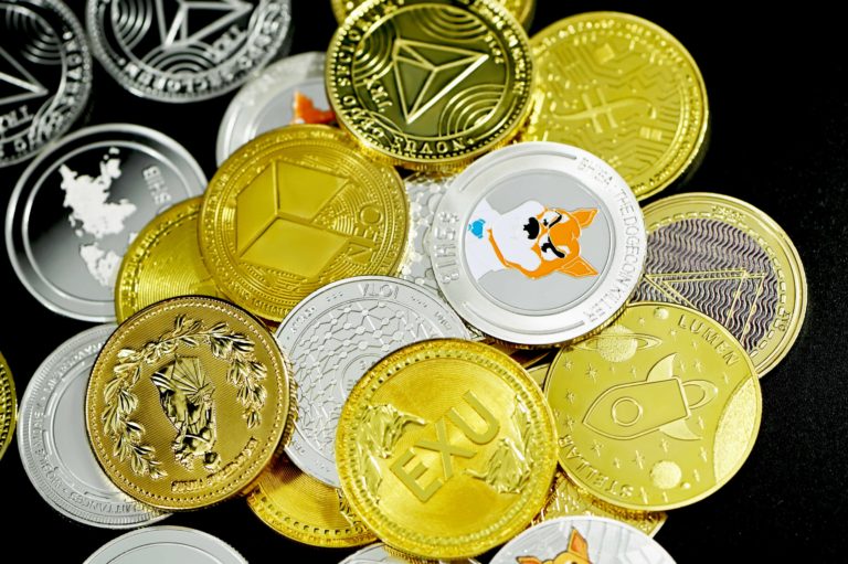 Various gold and silver cryptocurrency coins in a pile together.