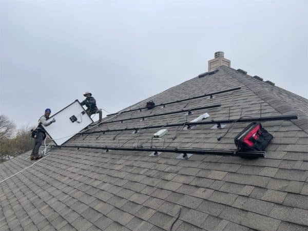 Two technicians installing solar panels of roof