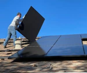 A contractor removing solar panels from a residential roof.