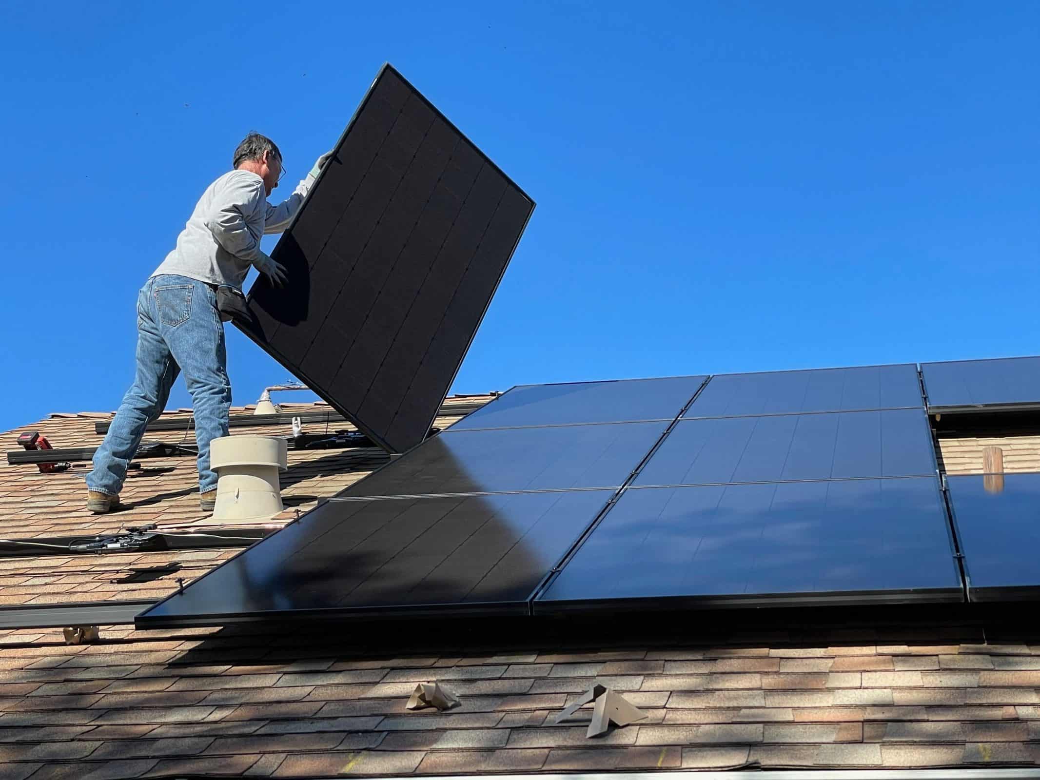A contractor removing solar panels from a residential roof.