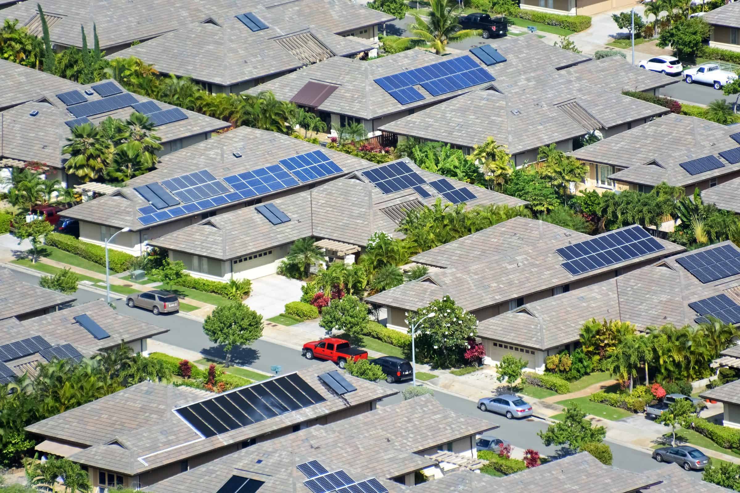 Bird's eye view of a neighborhood with solar panels on installed on various roofs.